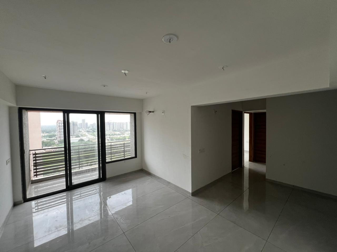 Living room with balcony and open city view at Shivansh The Grove
